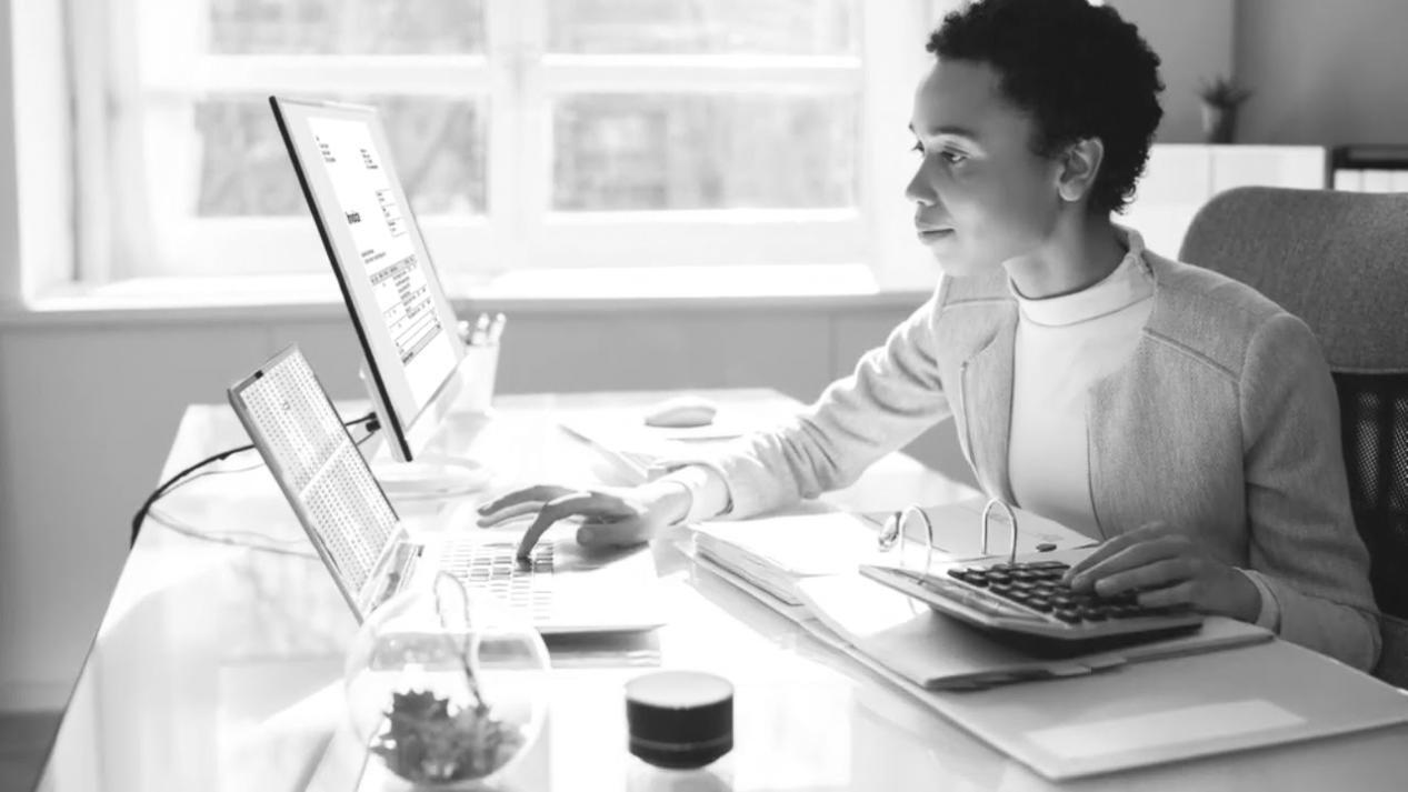 Professional workspace showing multiple monitors displaying financial data dashboards and contingency planning spreadsheets